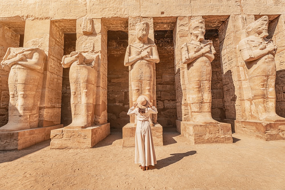 Uma garota turista feliz em um vestido está interessada em egiptologia e arqueologia e obtém uma experiência de viagem no Templo de Karnak em Luxor.