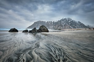 雪が積もった冬のノルウェー海のフィヨルドの岩だらけの海岸。スカグサンデン ビーチ、ロフォーテン諸島、ノルウェー