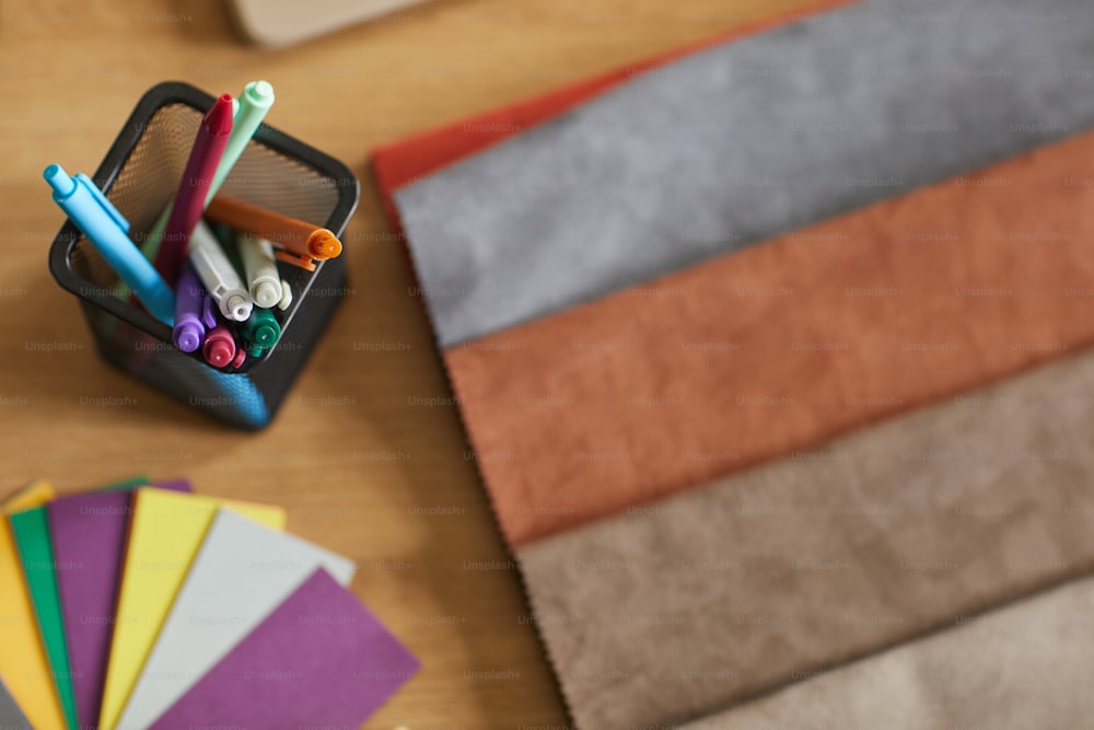 Close-up of colored markers and fabric samples on the workplace of designer