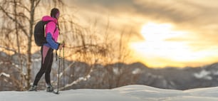 スノーシューハイキングで夕日を眺めるスポーティな女の子