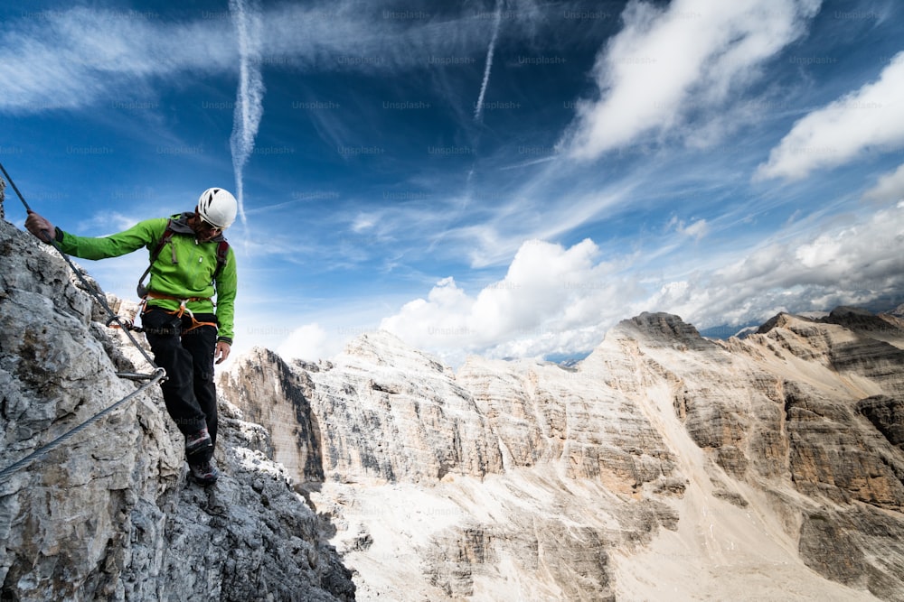 alpinista masculino em uma íngreme e exposta Via Ferrata com uma vista fantástica no sul do Tirol, nas Dolomitas italianas
