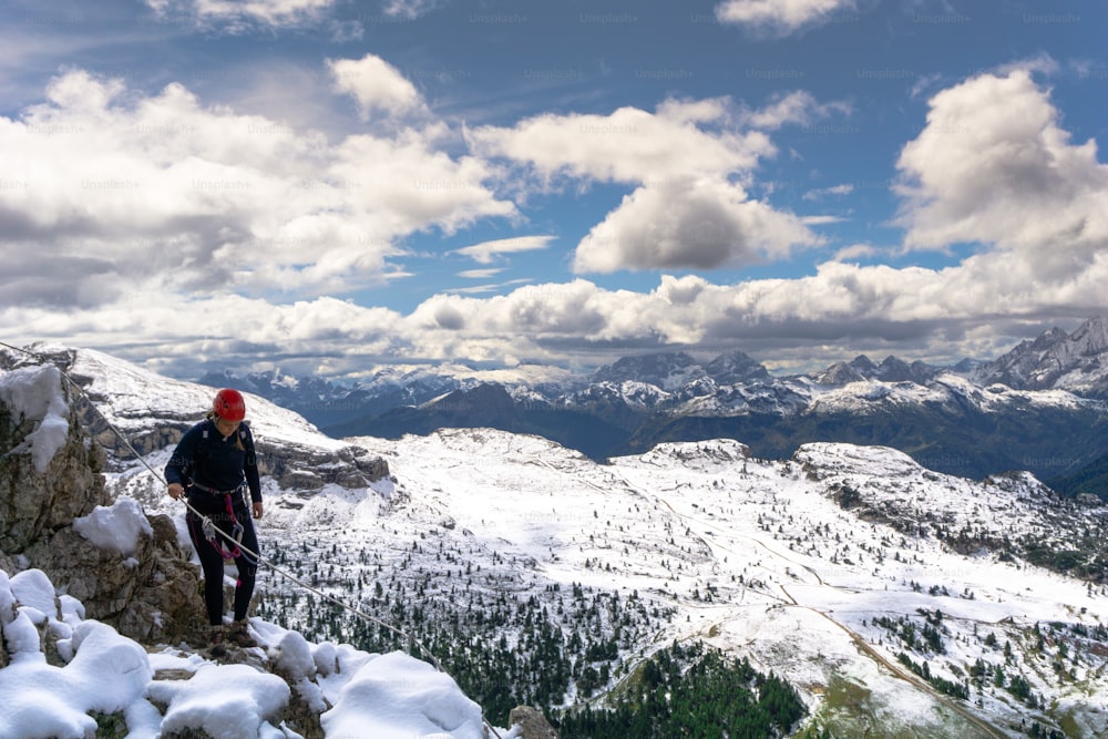 Jeune grimpeuse sur une Via Ferrata sur une arête enneigée et exposée dans le Tyrol du Sud dans les Dolomites italiennes