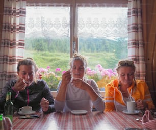 Vista de tres jóvenes alpinistas disfrutando de un café caliente en un refugio de montaña después de una dura escalada