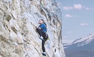 Erwachsene Frau Klettererin. Kletterer klettert auf eine Felswand. Frau macht harte Bewegung
