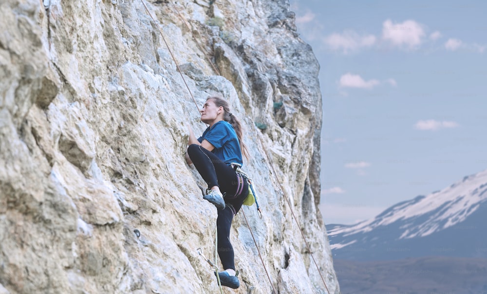 adult woman rock climber. rock climber climbs on a rocky wall. woman makes hard move