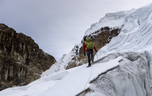 남성 산악 가��이드는 페루 안데스 산맥의 코르 디 예라 블랑카에있는 높은 정상으로가는 길에 가파르고 위험한 빙하를 건너고 있습니다.