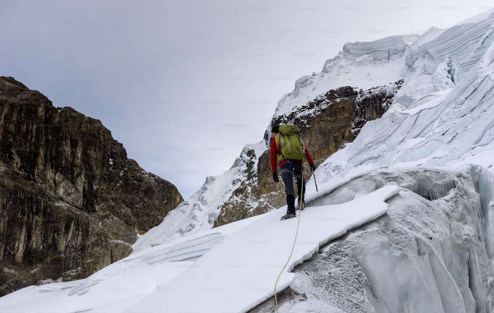 Un guide de montagne traverse un glacier escarpé et dangereux pour atteindre un haut sommet de la Cordillère Blanche dans les Andes au Pérou