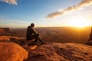 Excursionista se encuentra con la puesta de sol en el punto de vista Grand en el Parque Nacional Canyonlands en Utah, EE. UU.