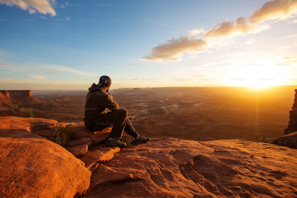 Excursionista se encuentra con la puesta de sol en el punto de vista Grand en el Parque Nacional Canyonlands en Utah, EE. UU.