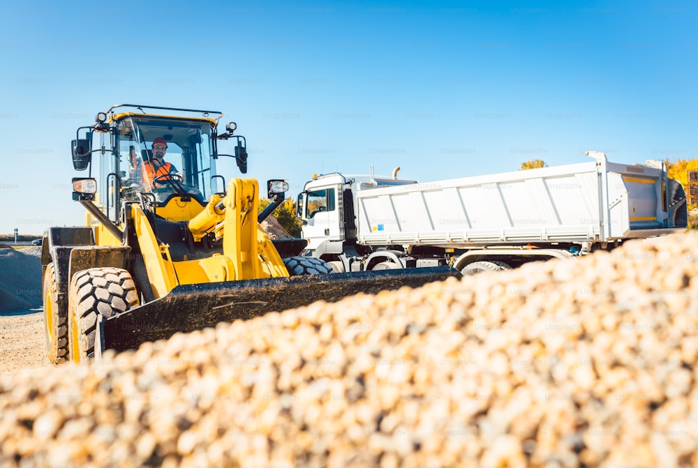 Construction workers doing earthworks with wheel loader and rubble truck