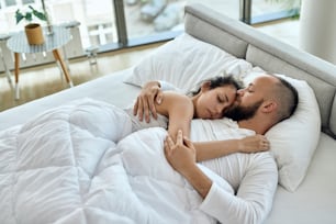 Young couple enjoying while sleeping embraced in the bedroom.