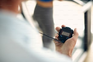 Close-up of personal trainer using stopwatch during exercise class in a gym.