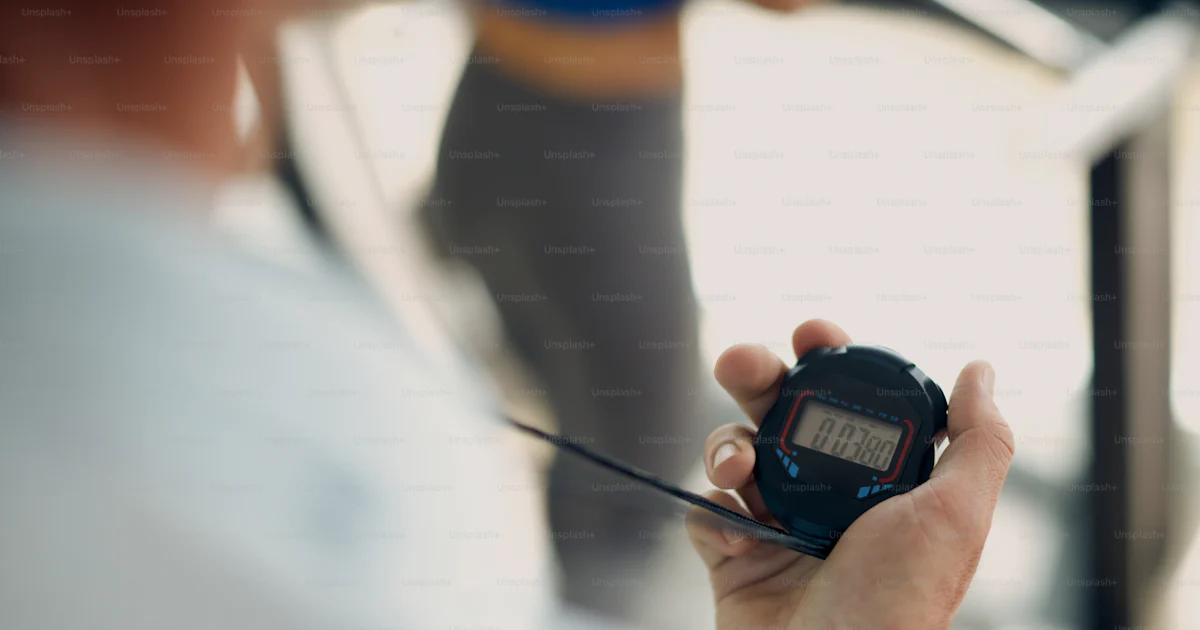 Close-up of personal trainer using stopwatch during exercise class in a ...