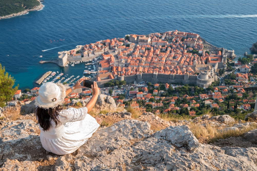Traveller taking photograph of Dubrovnik Old Town with mobile phone from aerial view. Dubrovnik old town was listed as UNESCO World Heritage Site in 1979.