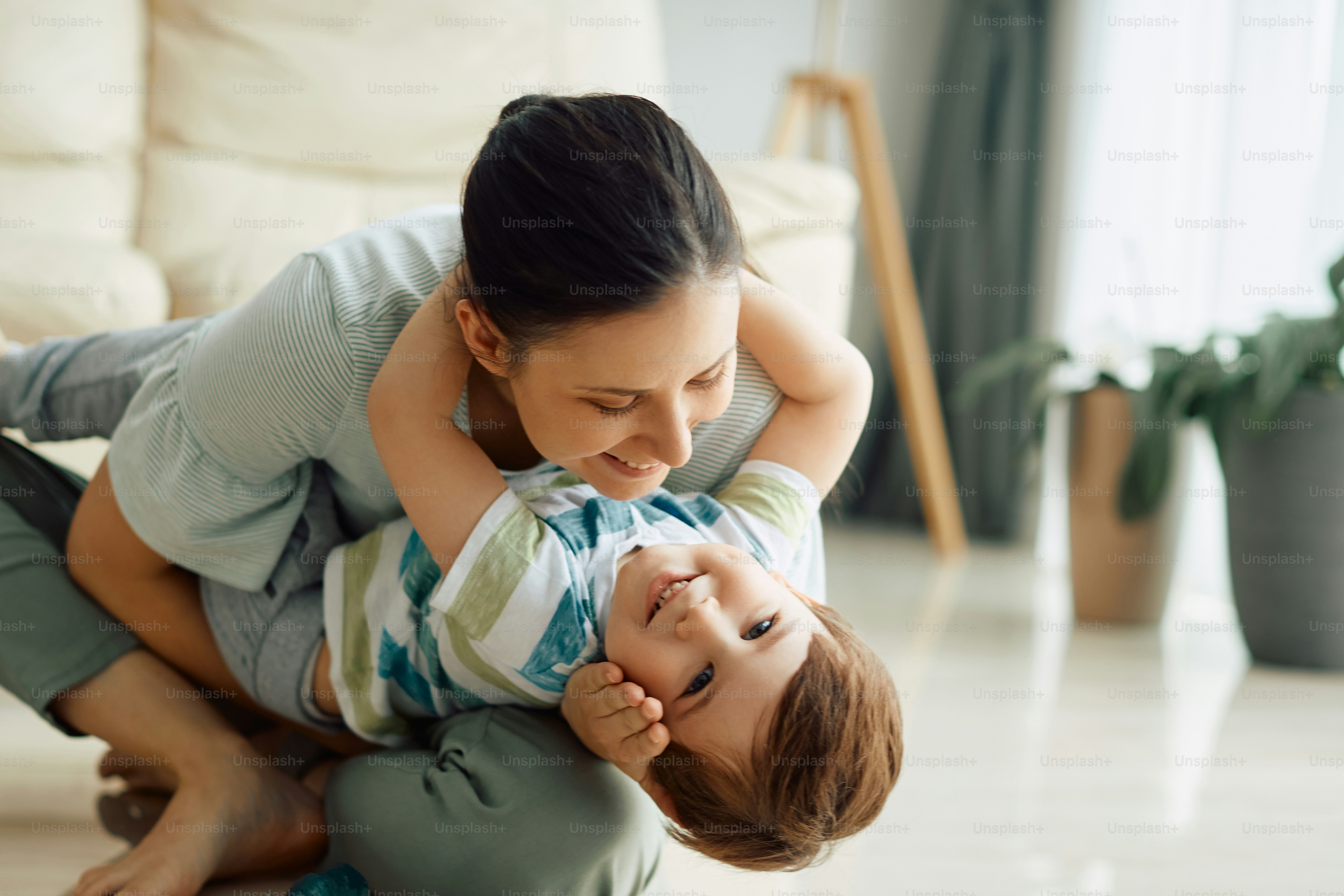 Niño feliz divirtiéndose con su madre juguetona en casa. Espacio de ...