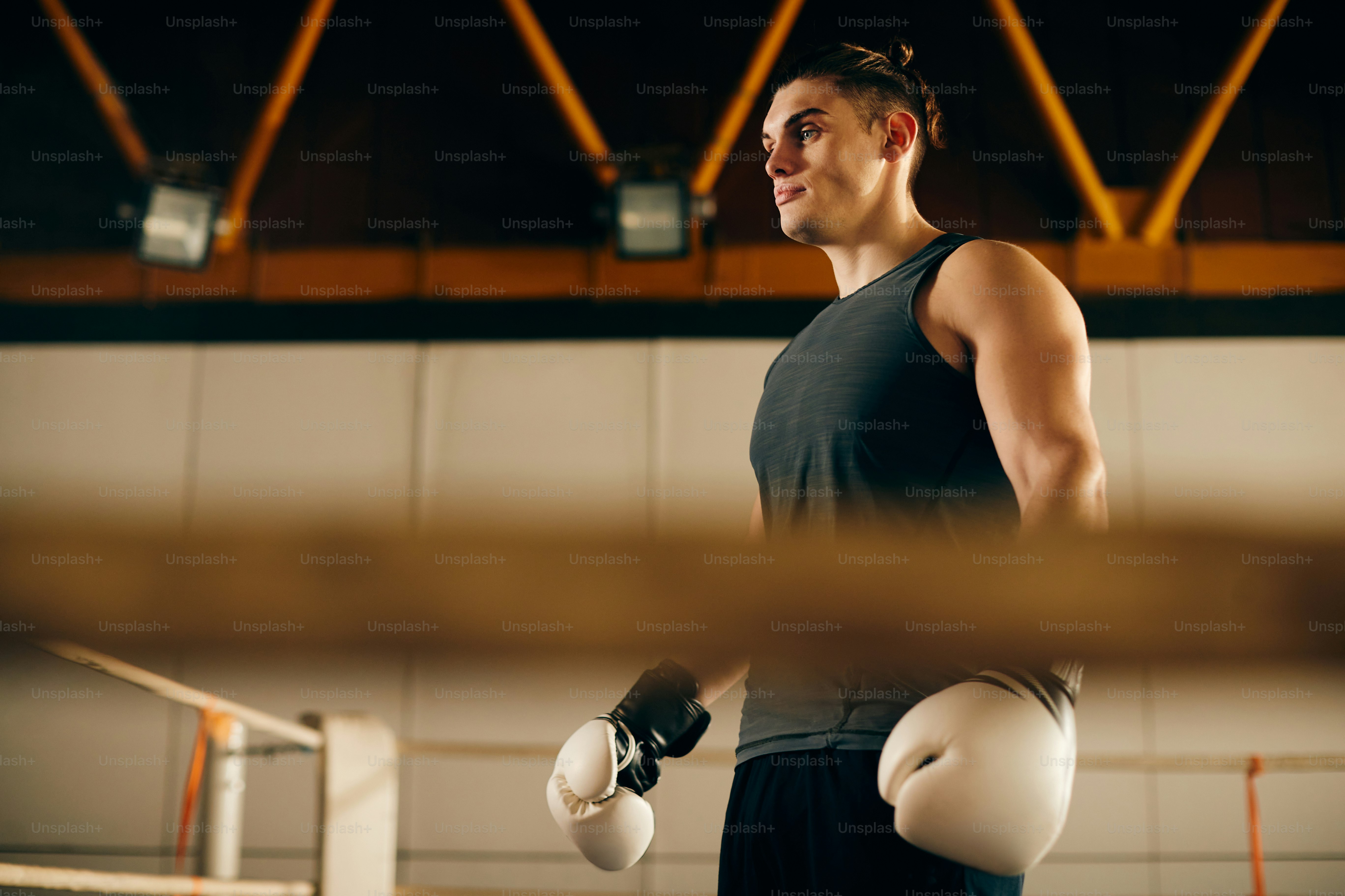Sotto vista di un giovane combattente pensieroso che esercita la boxe in una palestra.
