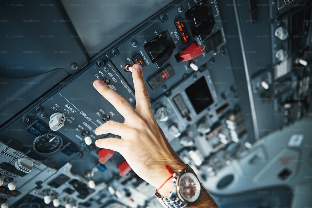 Gros plan d’une main d’un pilote touchant le commutateur dans un poste de pilotage et contrôlant l’amortisseur de lacet