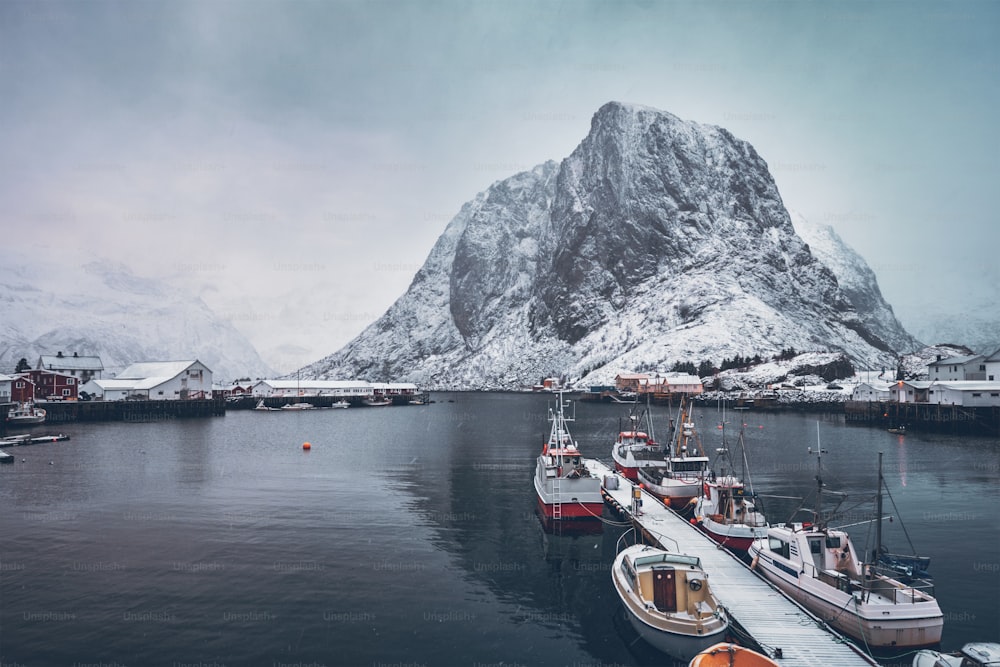 Cais com navios na vila de pescadores de Hamnoy nas Ilhas Lofoten, Noruega com casas de rorbu vermelho. Com neve caindo