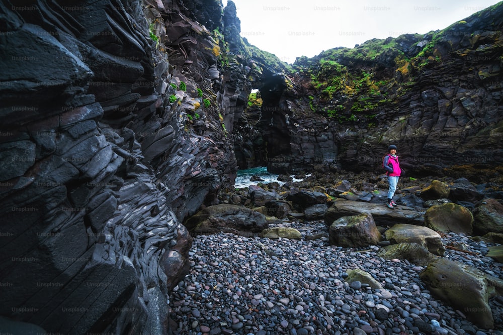 Viajero haciendo senderismo en el paisaje costero rocoso de Hellnar, Islandia. Hellnar era uno de los pueblos pesqueros más grandes bajo la capa de hielo de Snaefellsjökull, en el oeste de Islandia.