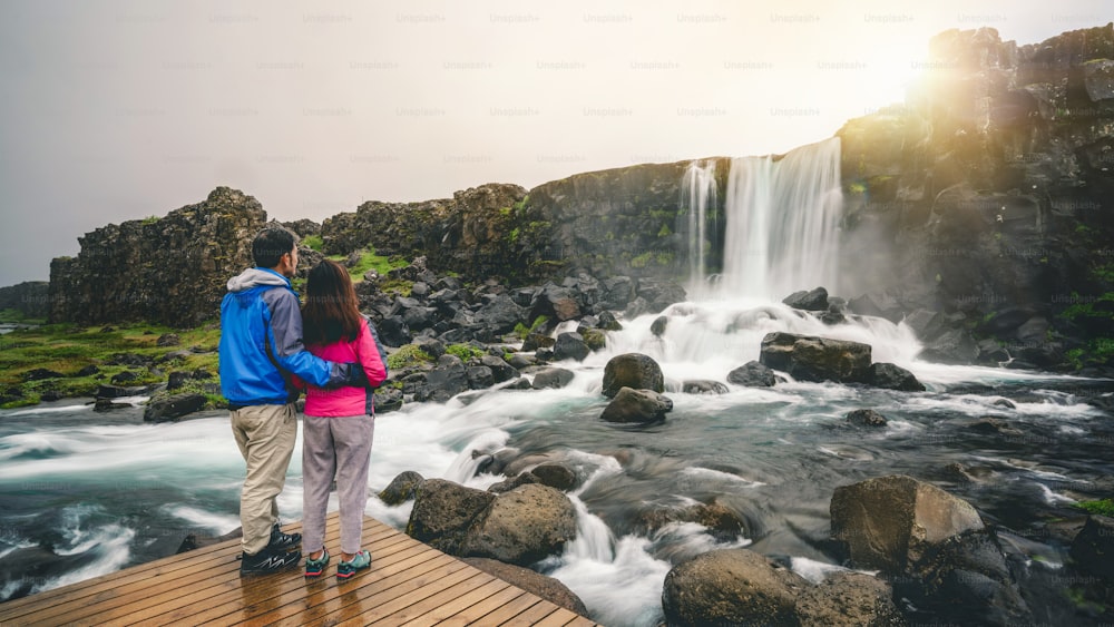 Viajantes de casal viajam para a cachoeira Oxararfoss no Parque Nacional Thingvellir, Islândia. Cachoeira Oxararfoss é famosa cachoeira atraindo turistas para visitar Thingvellir.