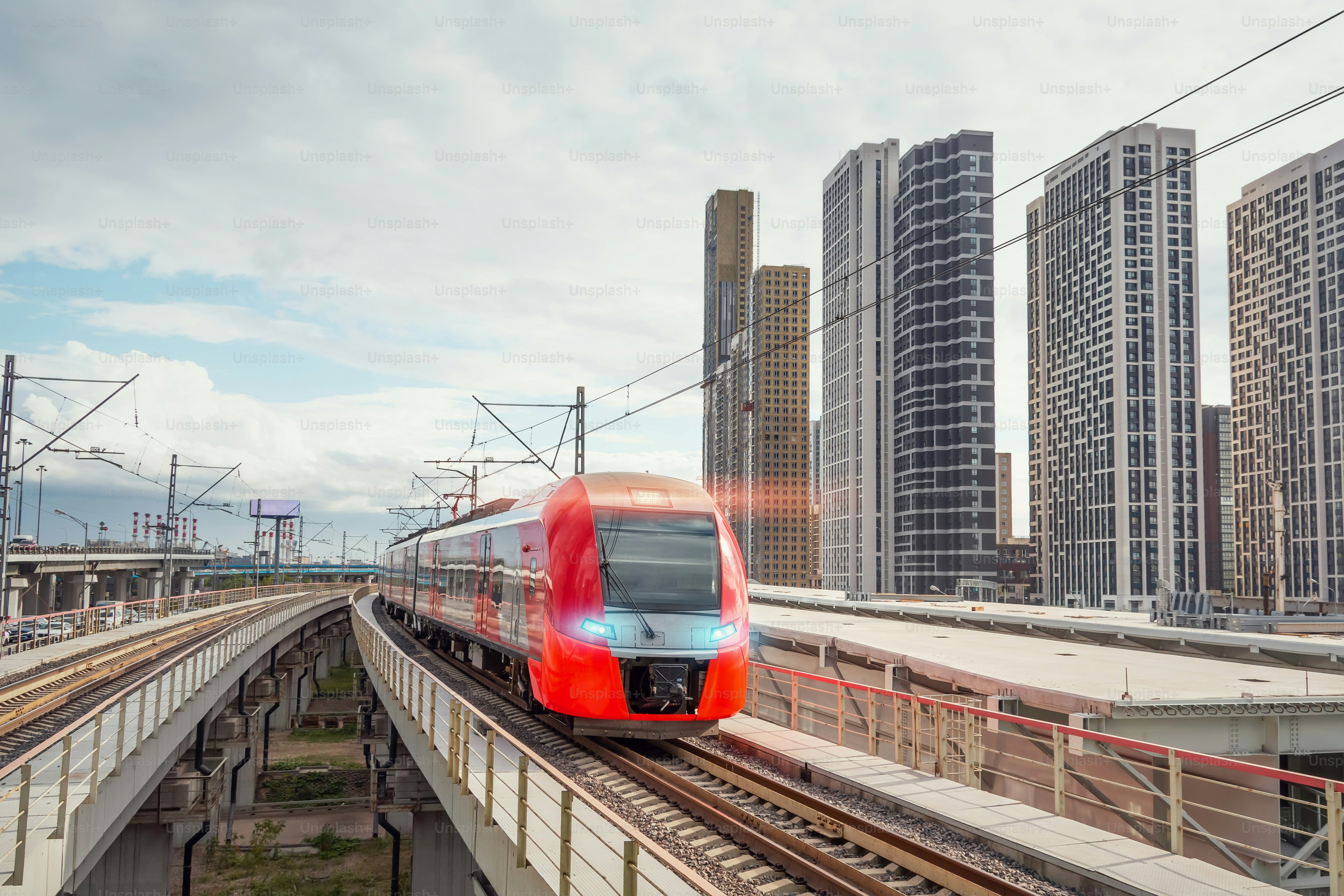 Electric passenger train drives at high speed among modern urban landscape