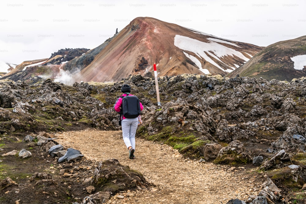 Escursionismo del viaggiatore a Landmannalaugar paesaggio naturale surreale nell'altopiano dell'Islanda, nordico, Europa. Bellissimo terreno di montagna innevato, colorato famoso per il trekking estivo, l'avventura e le passeggiate all'aria aperta.