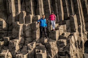 Viajante viajar para a formação rochosa vulcânica única na praia de areia preta da Islândia localizada perto da aldeia de Vik i myrdalin Sul da Islândia. Rochas colunares hexagonais atraem turistas que visitam a Islândia.