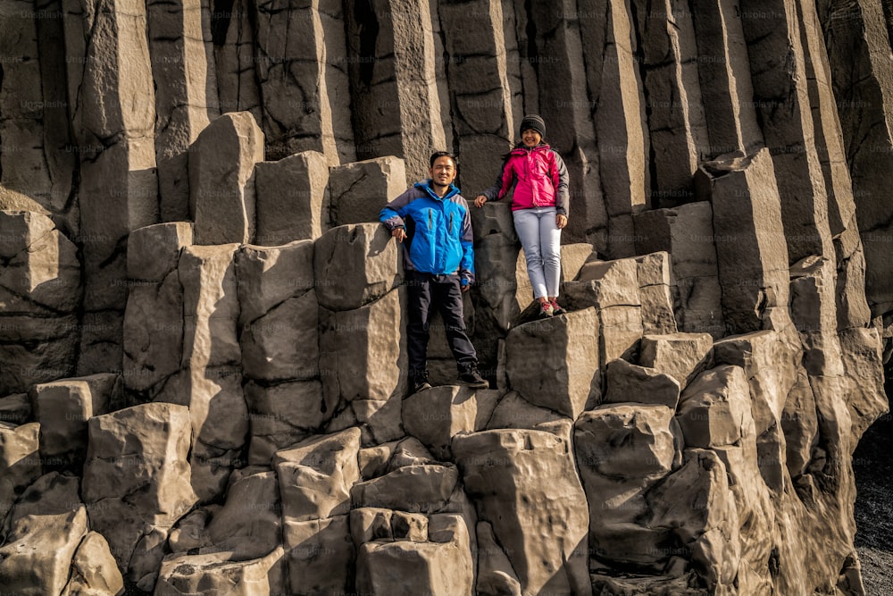Viajante viajar para a formação rochosa vulcânica única na praia de areia preta da Islândia localizada perto da aldeia de Vik i myrdalin Sul da Islândia. Rochas colunares hexagonais atraem turistas que visitam a Islândia.