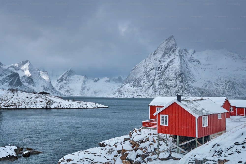 ノルウェーのロフォーテン諸島にある象徴的なハムノイ漁村で、赤いロルブの家があります。冬に雪が降る。