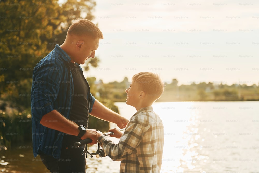 Father and son on fishing together outdoors at summertime.