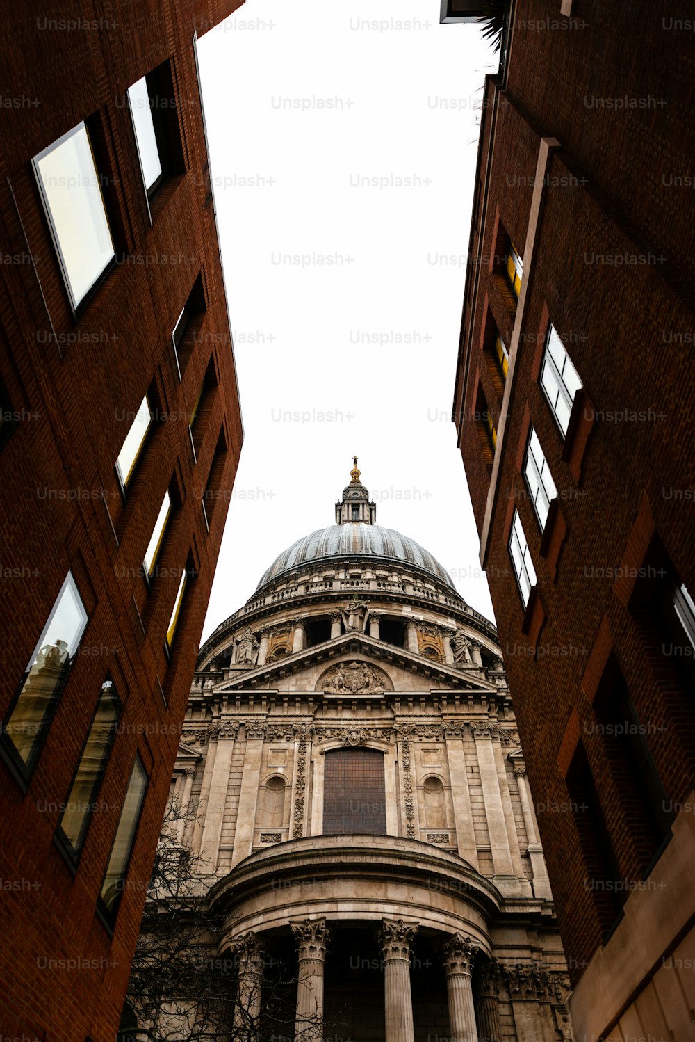 Side view of St.Paul’s Cathedral in London as seen through a narrow street. Built after The Great Fire Of London of 1666, it's Christopher Wren’s masterpiece and one of the most touristic attractions in the city.