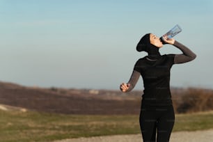 Young athletic woman refreshing herself with water while running in nature. Copy space.
