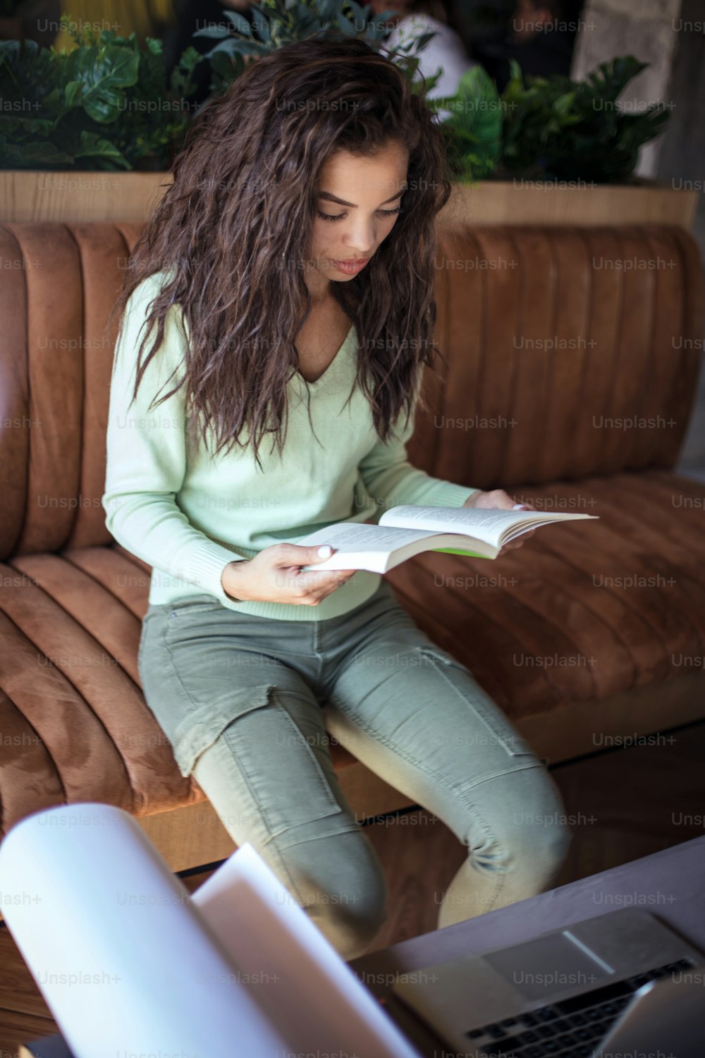 Time for new lesson. Young student girl at cafe reading book.