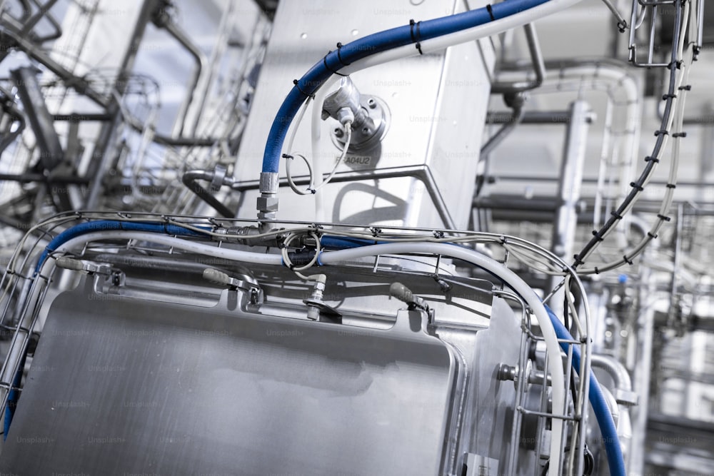 Production chrome background with blue hose around the tank. Metal pipes close-up. Industrial plant inside view. Rectangular metal pipes . Steel materials, construction supplies