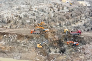 Vue aérienne de la fosse avec pieux du bâtiment, démolition. Les camions et les excavatrices effectuent des travaux d’enlèvement de terre