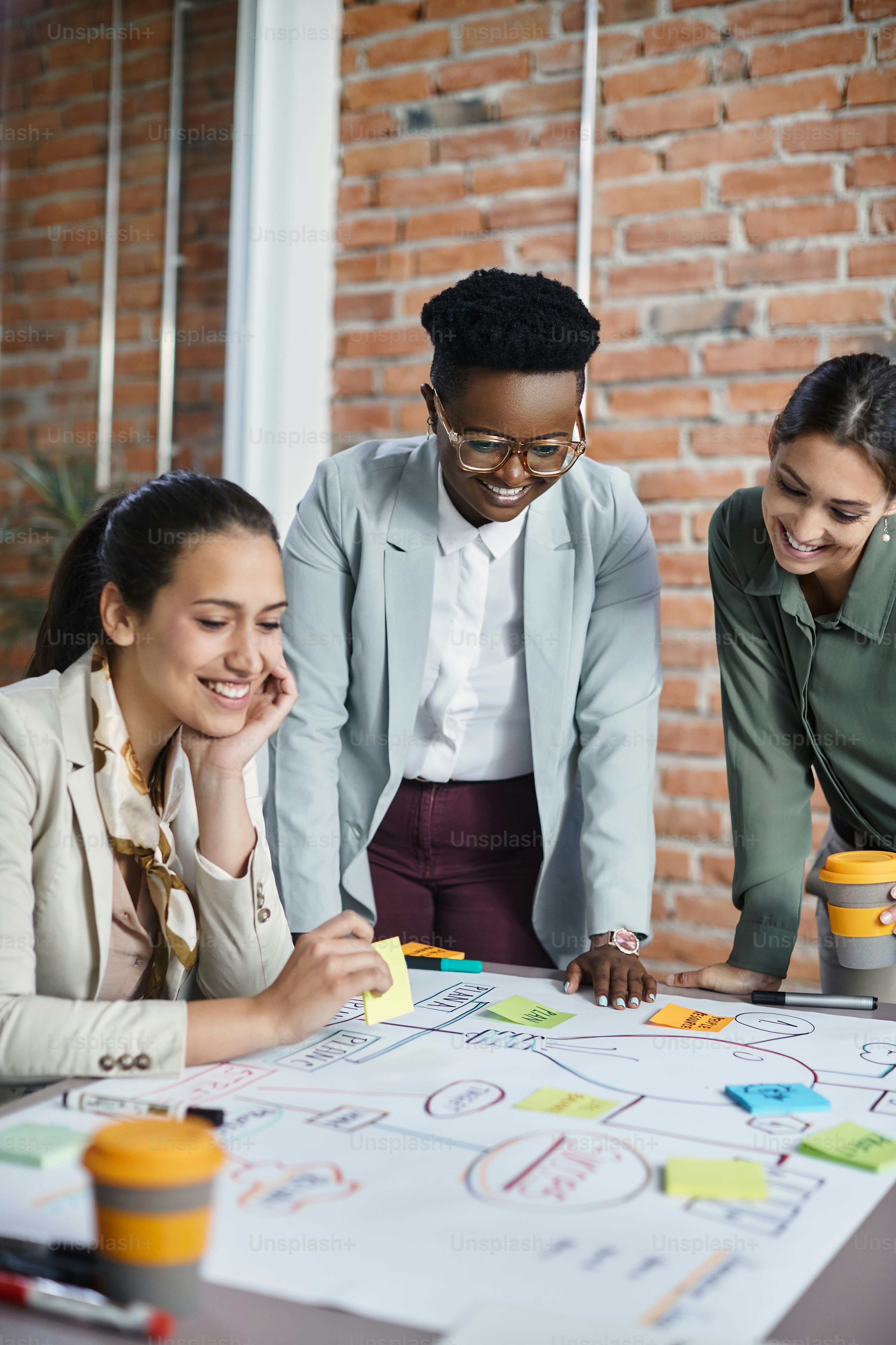 Multirassische Gruppe von Geschäftsfrauen brainstorming, während sie an neuen Ideen arbeiten und eine Mindmap für ein Meeting im Büro erstellen