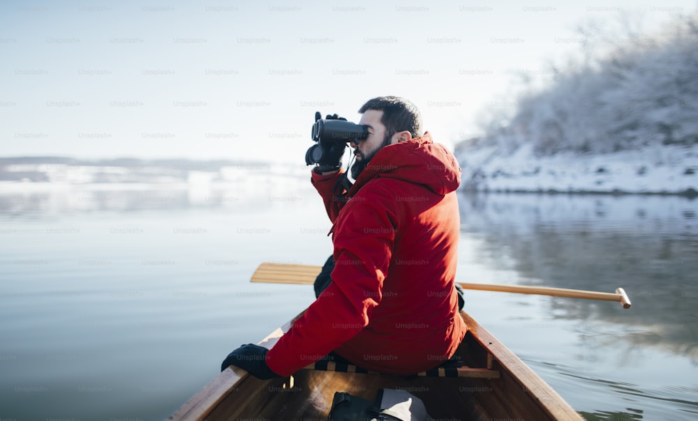 Side view of man watching birds from a canoe.