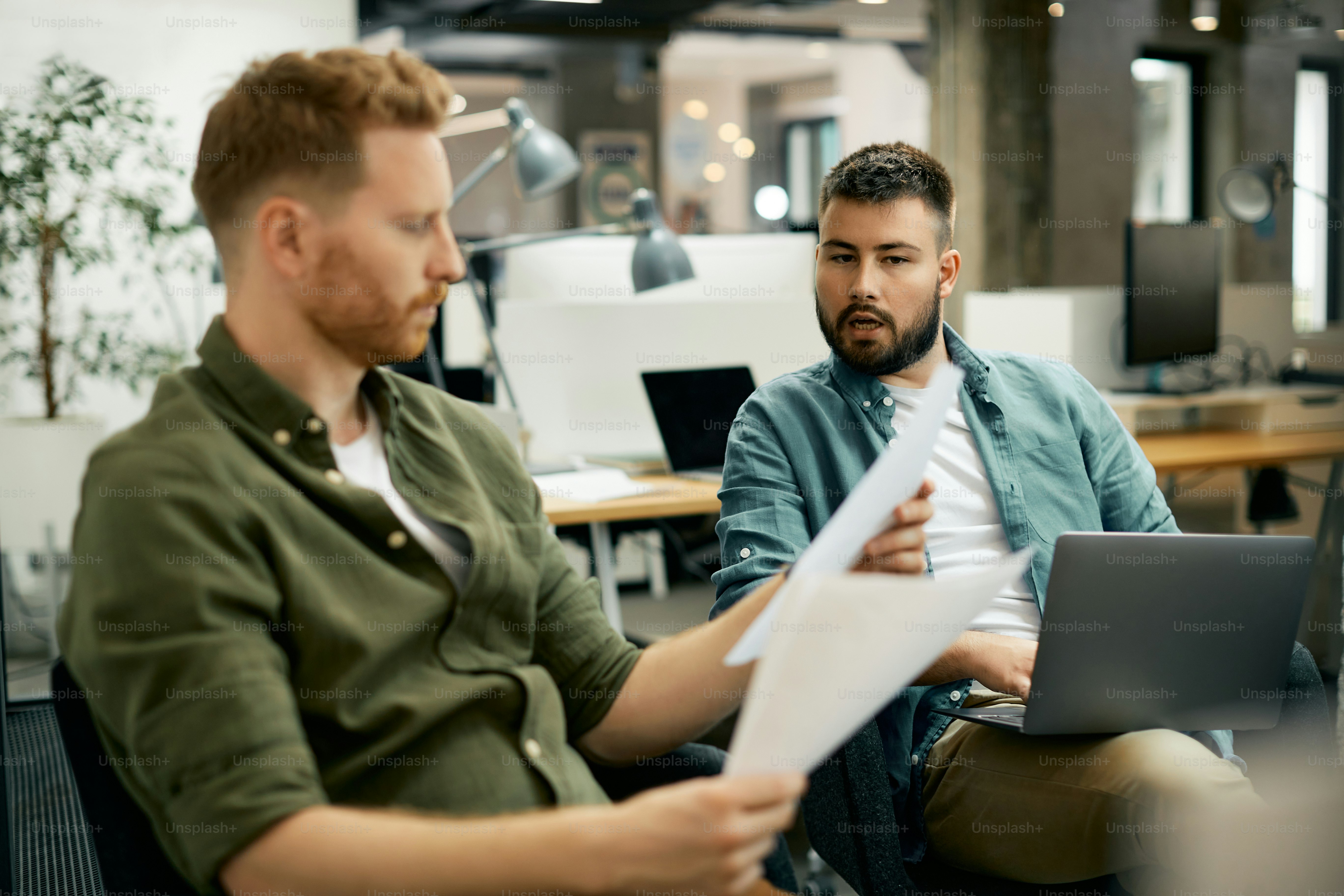 Young entrepreneur and his coworker analyzing business reports while working together in the office.