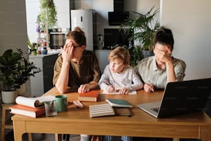 Upset homosexual mothers trying to teach their naughty son sitting at table with books in kitchen