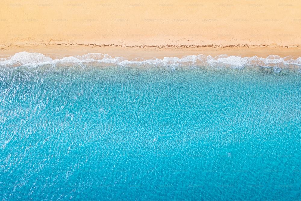 Luftaufnahme eines idyllischen Meeressandstrandes mit blauen Wellen und Kopierraum. Das Konzept von Urlaub in tropischen Ländern und Entspannung. Hintergrund für Reisen und Urlaub