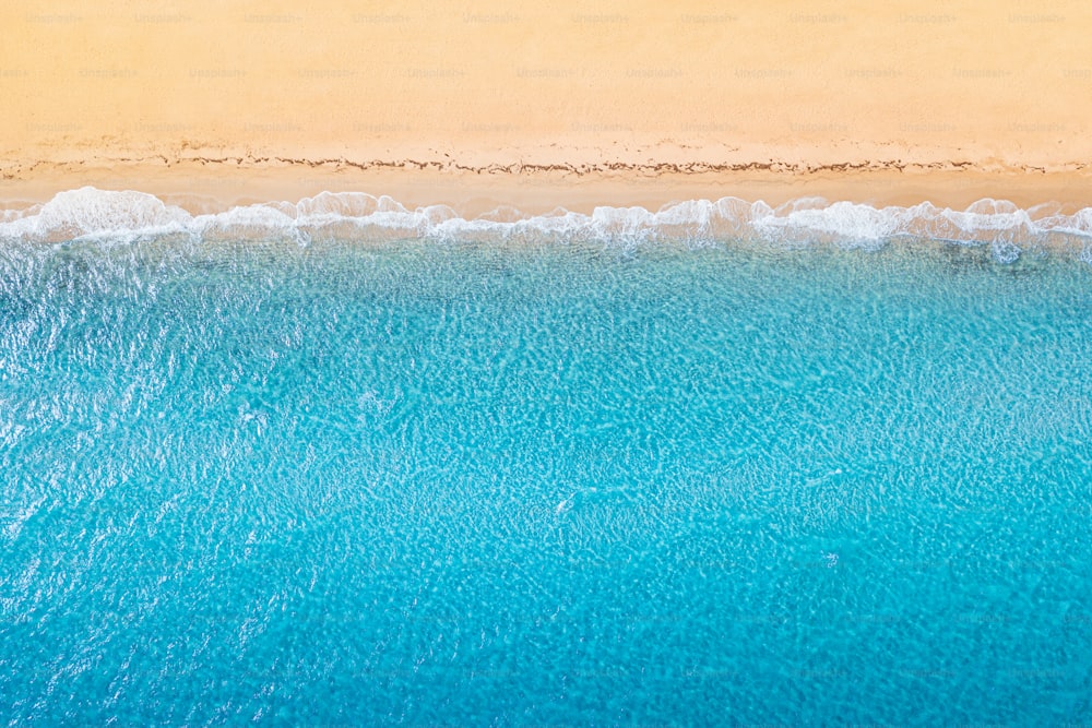 Aerial view of an idyllic sea sandy beach with blue waves and copy space. The concept of holidays in tropical countries and relaxation. Background for travel and vacation