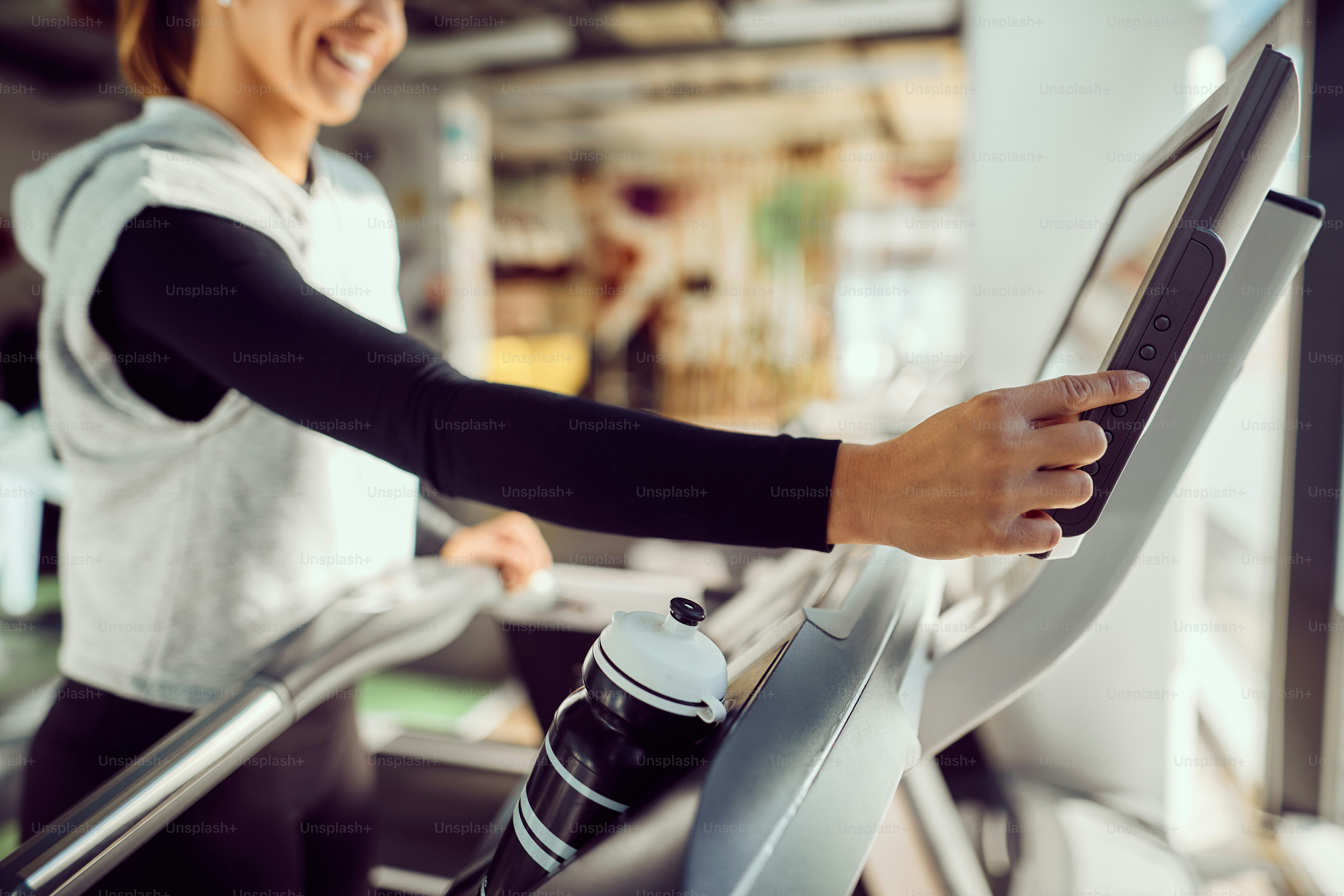 Close-up of athletic woman adjusting speed while exercising on treadmill at the gym.