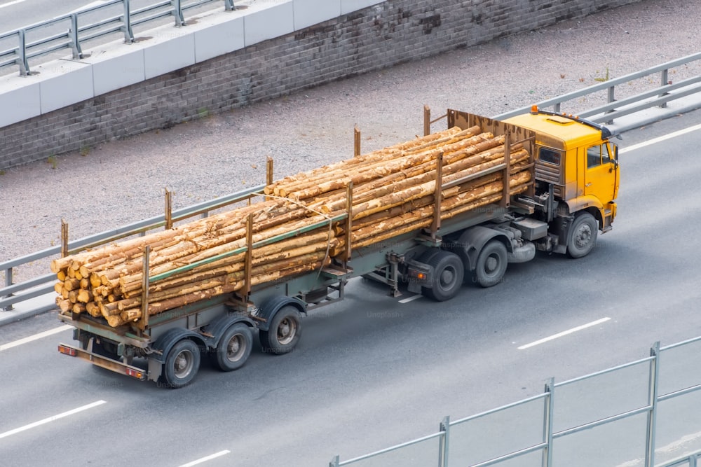 A timber truck drives along the city highway loaded with saw cut tree trunks