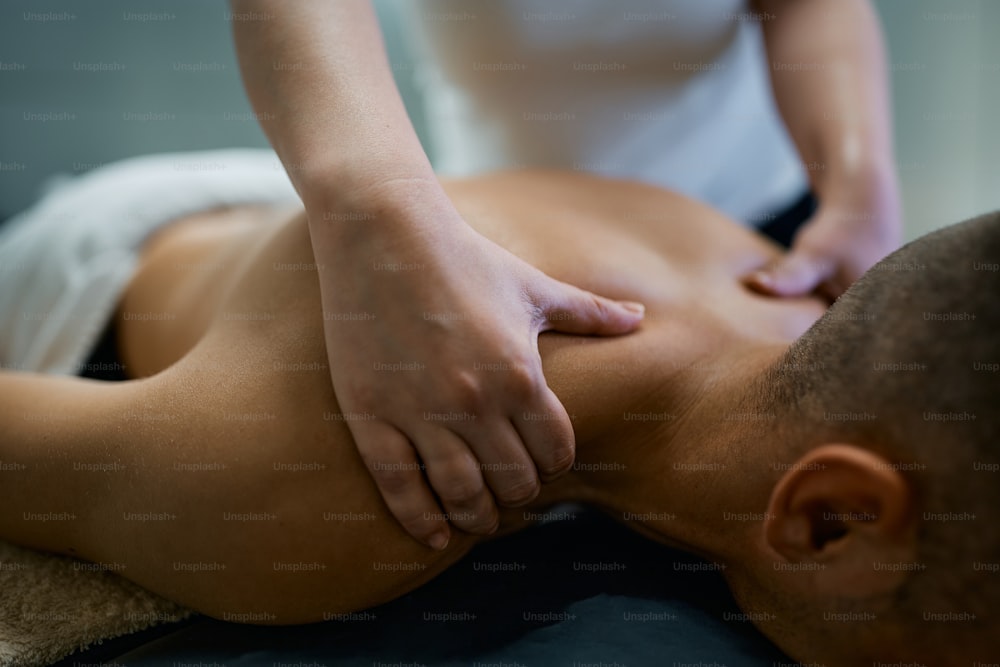 Close-up of massage therapist massaging man's shoulders.