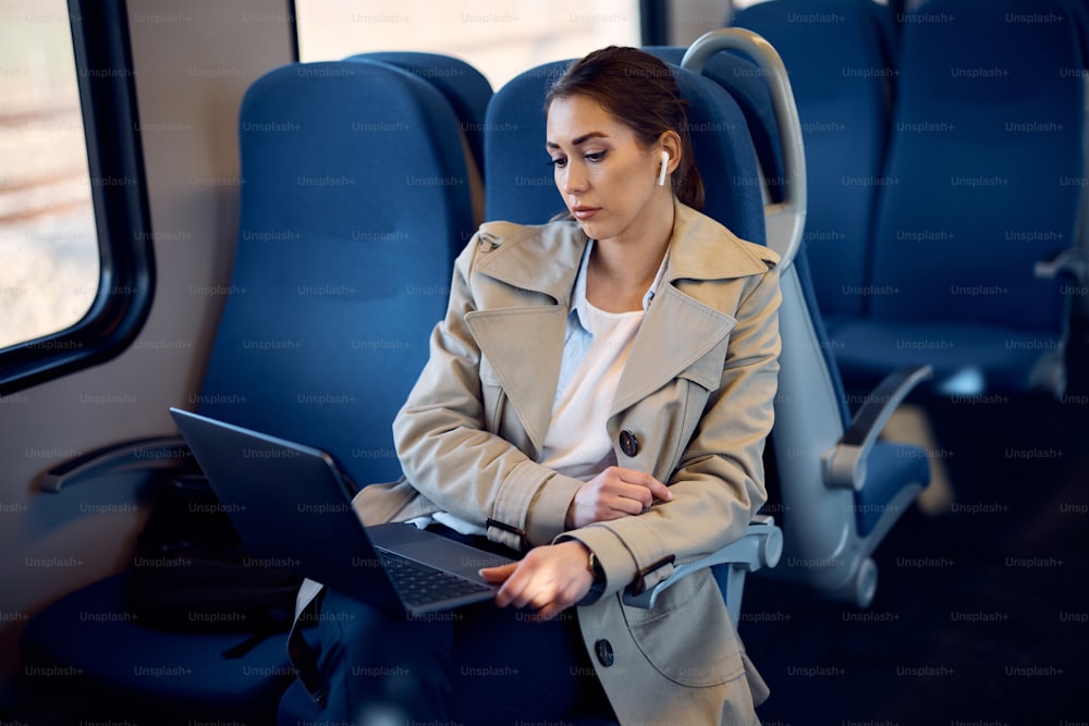 Junge Geschäftsfrau, die am Laptop arbeitet und mit dem Zug zur Arbeit pendelt.