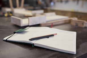 Primer plano del bloc de notas abierto con bolígrafo y bolígrafo sobre la mesa en la oficina