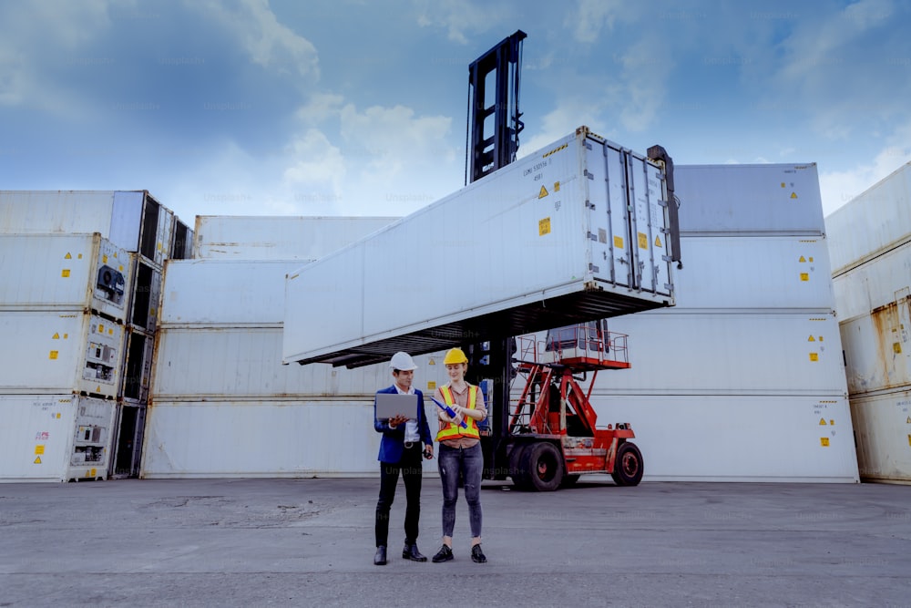 Manager and dock worker under discussion about dock container shipping warehouse document,they wearing safety uniform hard hat and hold radio communication