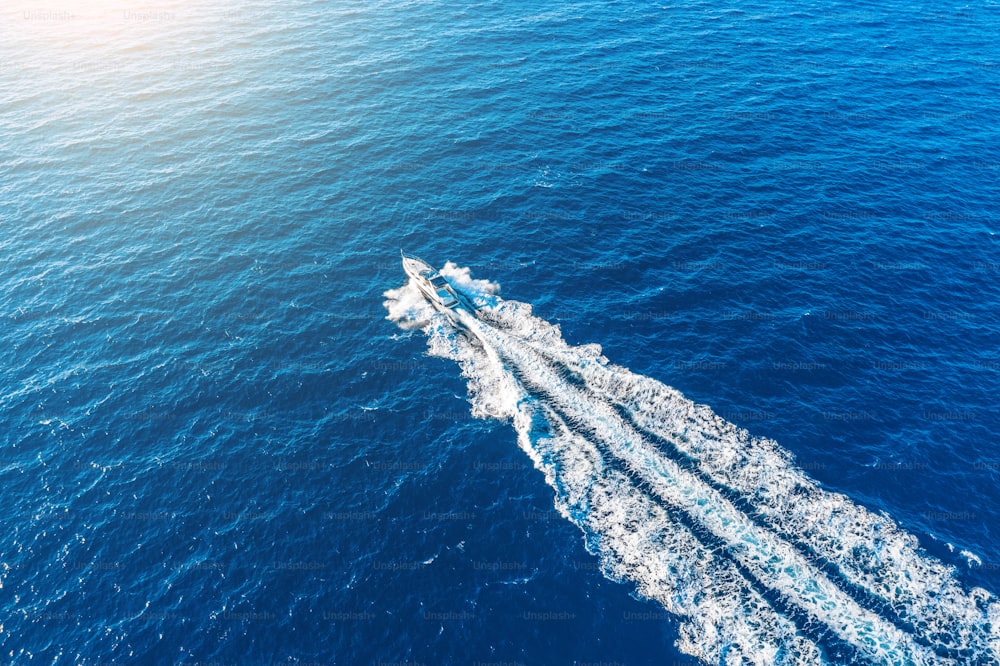 Bootsanleger mit hoher Geschwindigkeit schwimmt im Mittelmeer ins Sonnenlicht, Luftbild