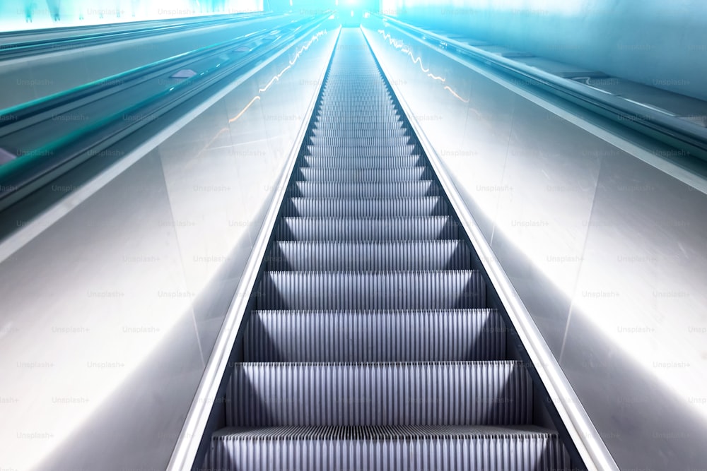 View escalator stairs rise to the top of the blue white shine light.