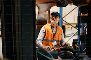 Opérateur de chariot élévateur mature chargeant des marchandises tout en travaillant à l’entrepôt de distribution.